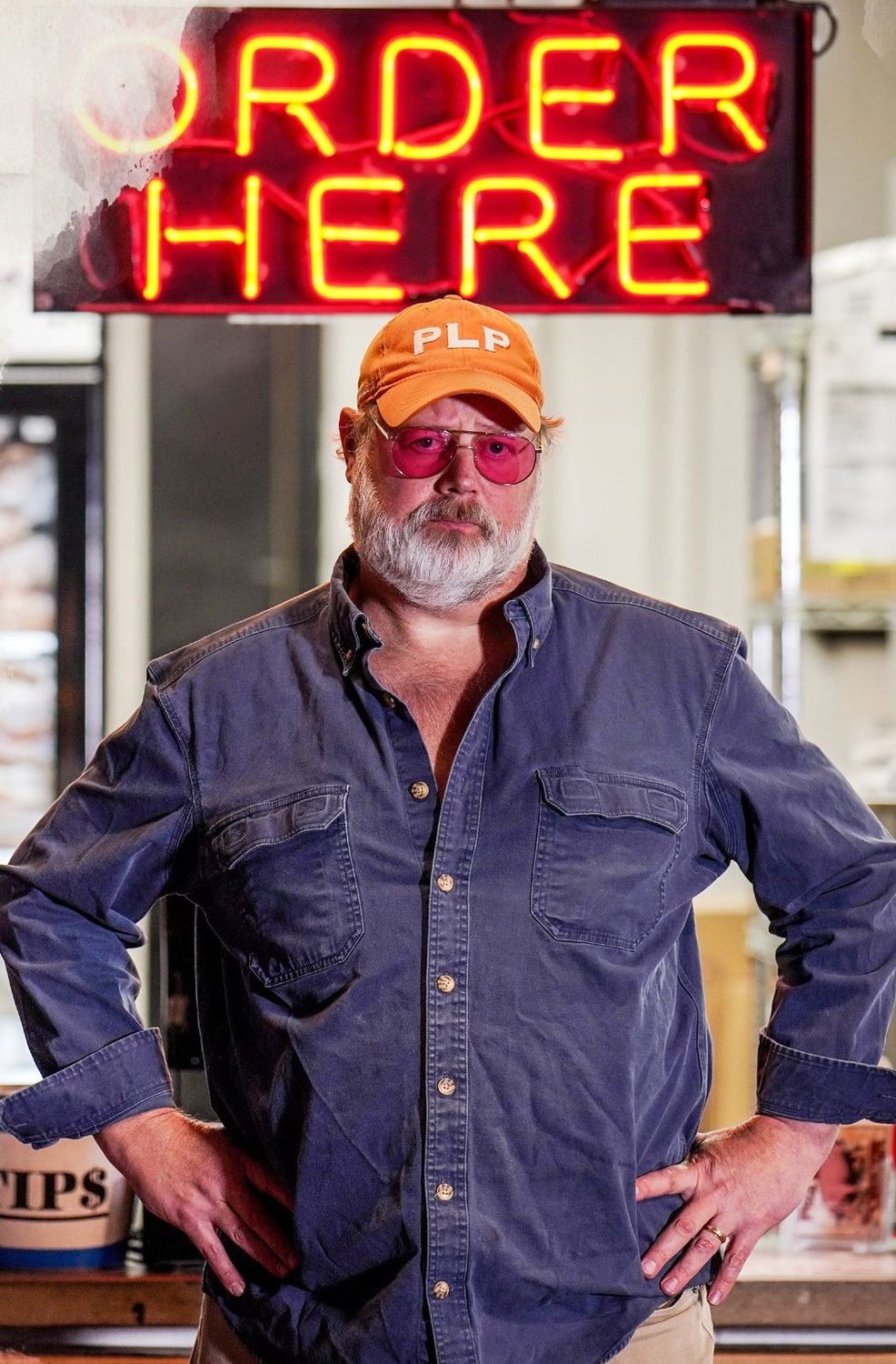 Carey Bringle in his orange PLP cap beneath an Order Here neon sign